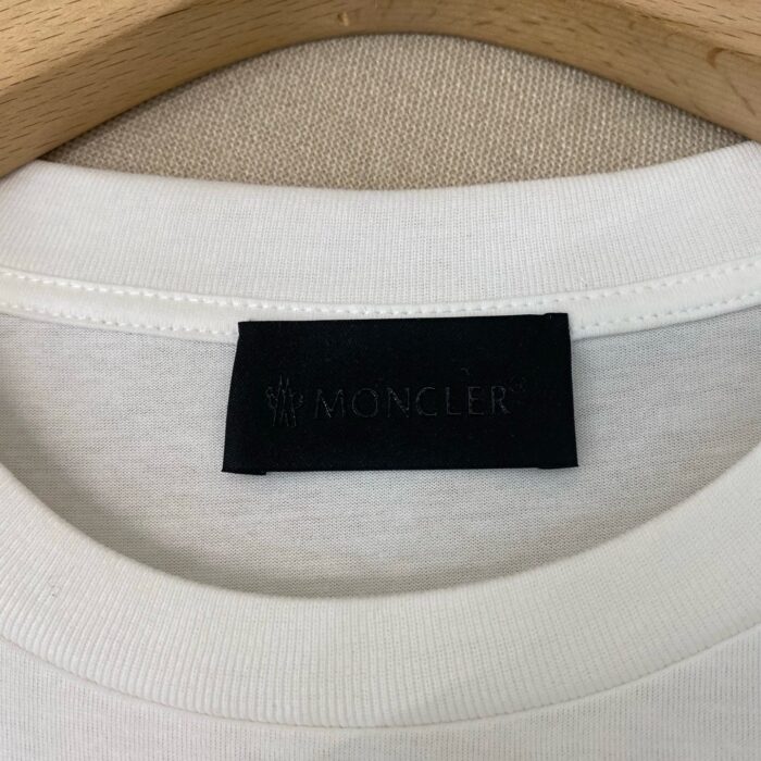 Etichetta Moncler sul colletto di maglietta bianca di alta qualità.