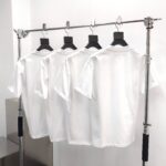 Esposizione minimalista di magliette bianche su attrezzatura moderna in boutique.