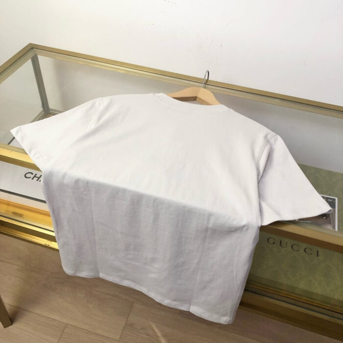 Maglietta bianca casual su gruccia in esposizione elegante con vetrina in stile minimalista.