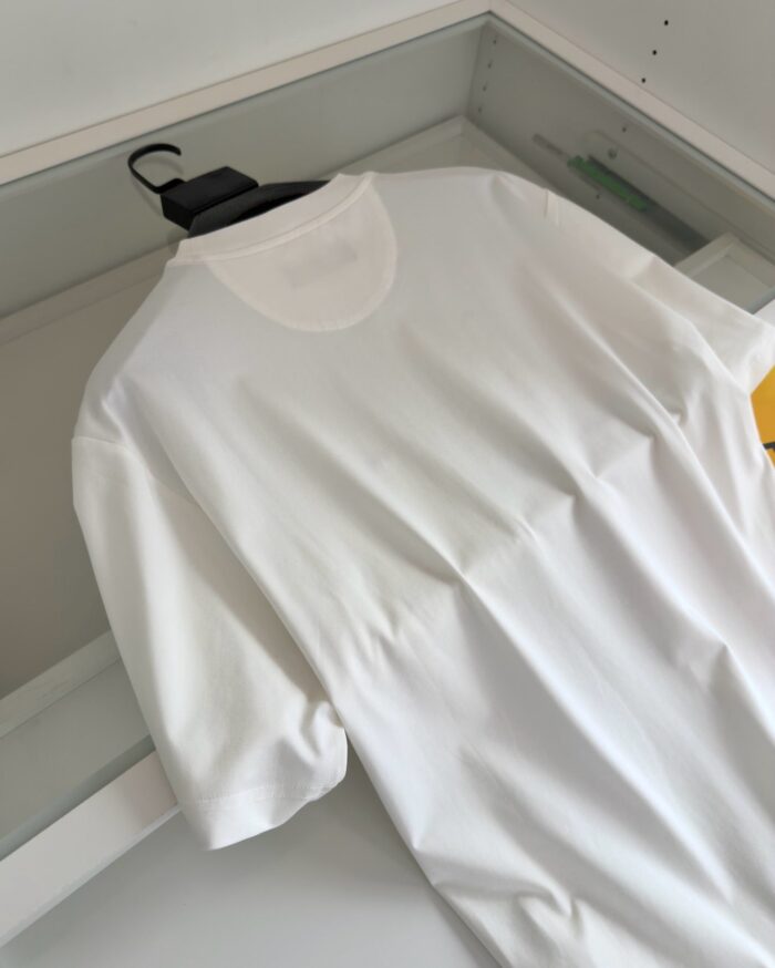 T-shirt bianca minimalista su un appendiabiti in un armadio ordinato, ideale per look casual ed eleganti.