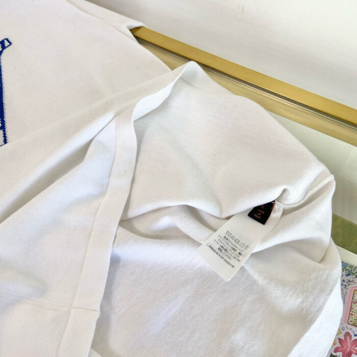 Maglietta bianca casual con dettaglio interno e etichetta, tessuto morbido e maniche corte.