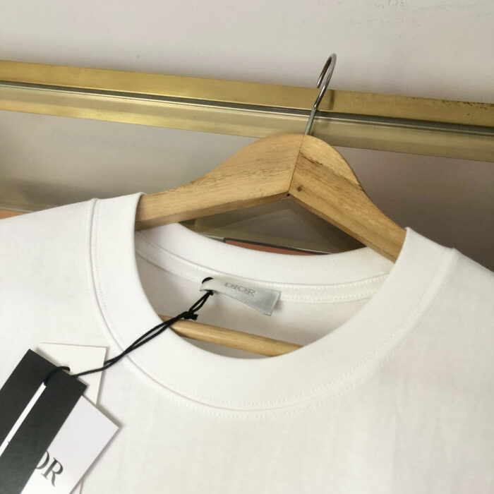 Maglietta bianca in cotone su appendiabiti in legno, stile minimalista e versatile.