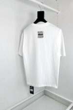 T-shirt bianca minimalista con etichetta MIA, vestibilità elegante, ideale per uno stile moderno e versatile.