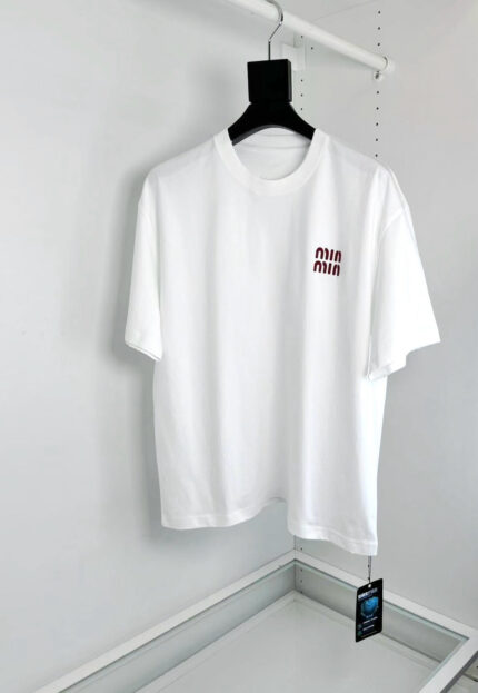 Maglietta bianca minimalista con logo piccolo sul petto, stile casual e moderno.