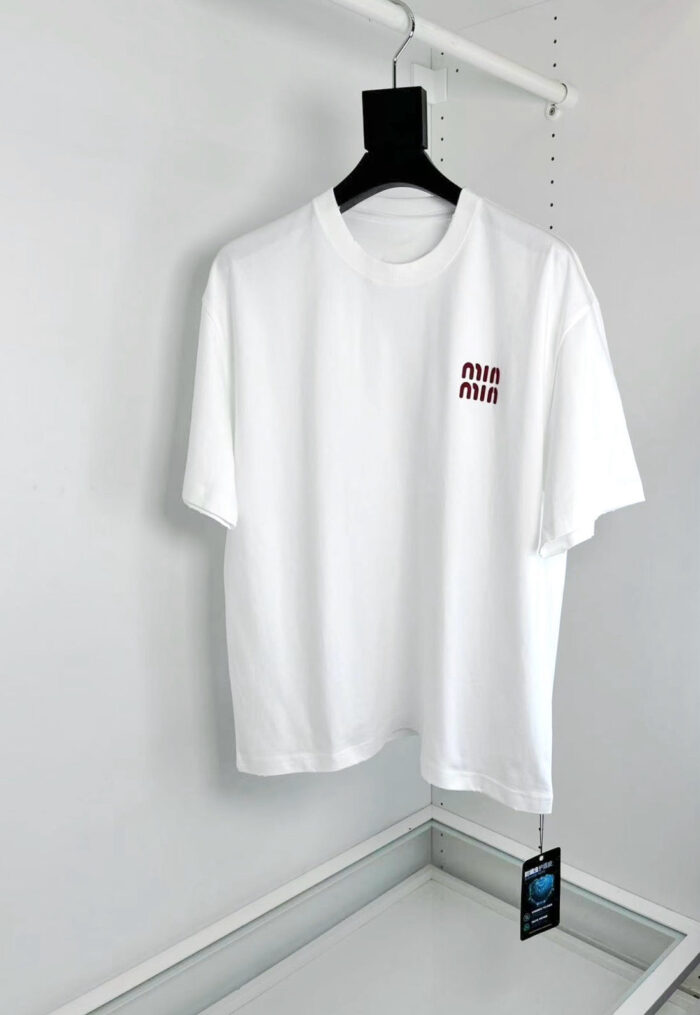 Maglietta bianca minimalista con logo piccolo sul petto, stile casual e moderno.