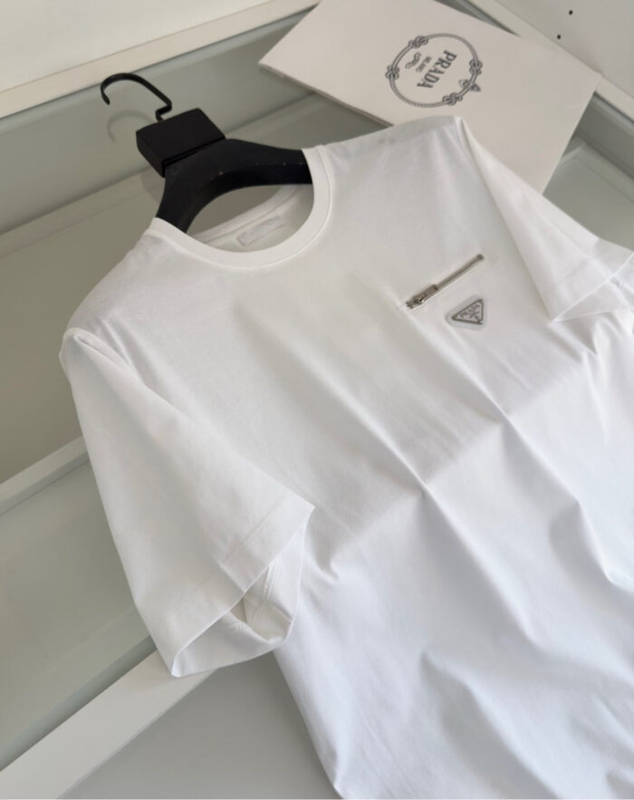 Maglietta bianca minimalista con tasca e dettaglio zipper argentato, stile elegante e versatile.