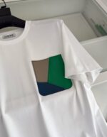 T-shirt bianco con tasca colorata patchwork, stile moderno e casual.