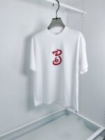 T-shirt bianca con grafica rossa artistica, stile minimalista, casual e moderna.