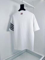 T-shirt bianco casual con strisce nere e dettaglio rosso, stile sportivo e versatile.