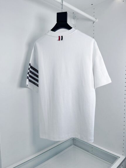 T-shirt bianco casual con strisce nere e dettaglio rosso, stile sportivo e versatile.