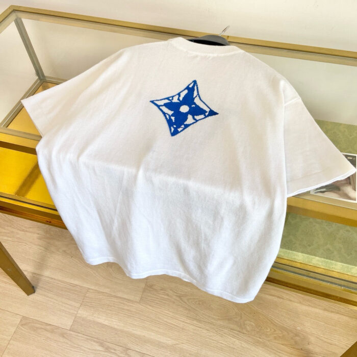 Maglietta bianca con grafica blu a stella su tavolo di vetro, stile minimalista e moderno.