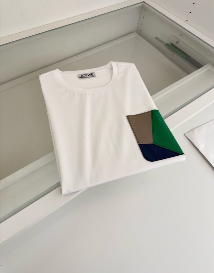 T-shirt bianco con tasca geometrica colorata, stile moderno e versatile per ogni occasione.