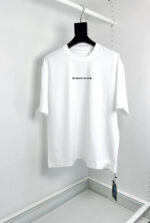 Maglietta bianca casual con logo minimalista, morbida e comoda, su appendiabiti in stile moderno.