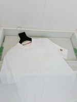 Maglietta bianca con logo e dettaglio rosso, stile casual e moderno in esposizione elegante.