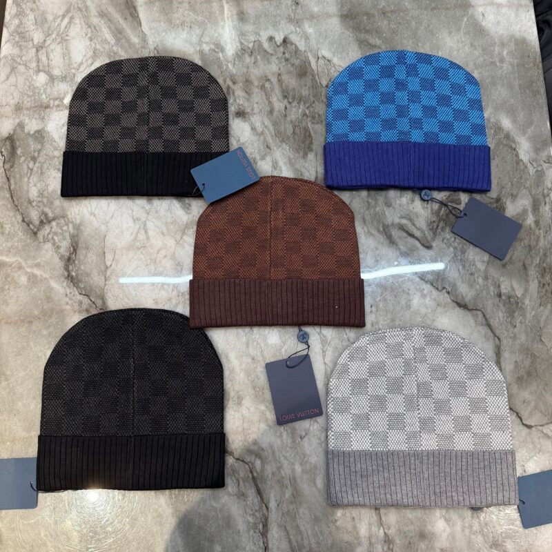 Cappelli beanie alla moda, vari colori, stili trendy su superficie di marmo chiaro.
