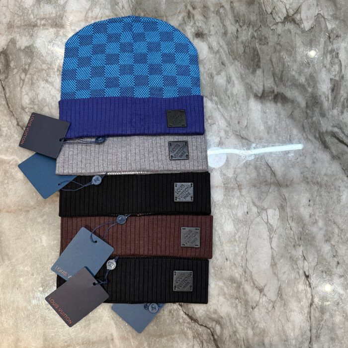 Collezione di cappelli beanie eleganti in vari colori e materiali su superficie di marmo.