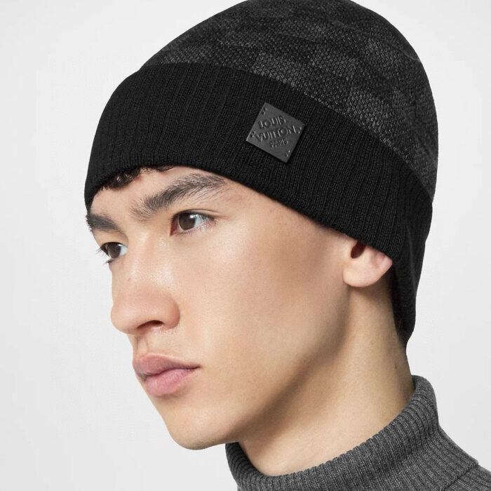 Uomo moderno con berretto nero e maglione grigio, stile casual e elegante.