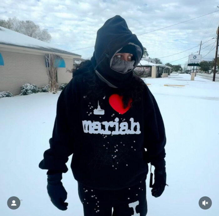 Persona con hoodie I Love Mariah e maschera in paesaggio innevato sereno.