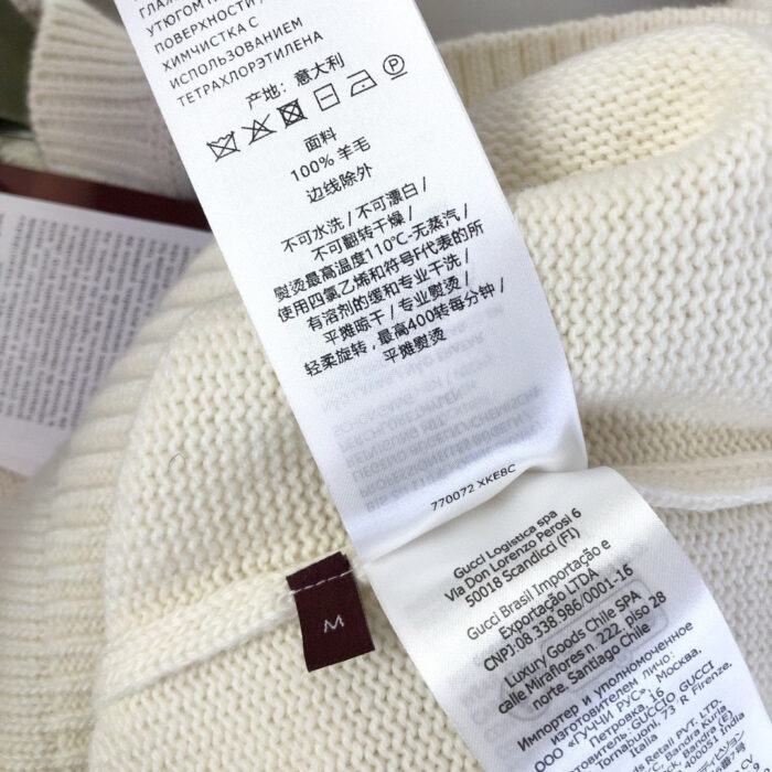 Etichetta di cura per maglione in lana con simboli e dettagli multilingua.