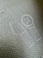Emblema in tessuto con design minimale di freccia e cerchio decorato, simbolo di riconoscimento.