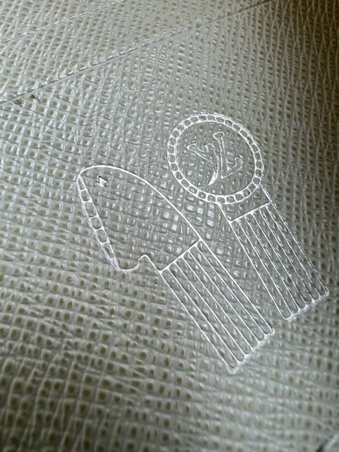 Emblema in tessuto con design minimale di freccia e cerchio decorato, simbolo di riconoscimento.