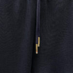 Dettaglio di tessuto nero, drizzina con aglet dorato, stile minimalista e confortevole.