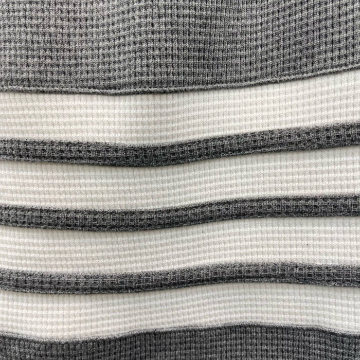 Tessuto a righe grigio e bianco con texture waffle, ideale per abbigliamento casual e confortevole.