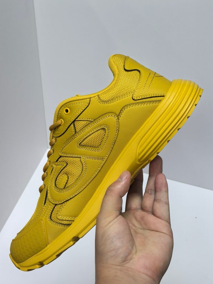 Scarpe da corsa gialle moderne con suola antiscivolo, tenute in mano, stile sportivo dinamico.