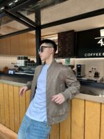 Giovane alla moda in caffè moderno, stile casual con occhiali, ambiente accogliente e raffinato.