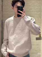 Ragazzo scatta selfie con maglione beige casual e stile moderno in ambiente caldo e accogliente.