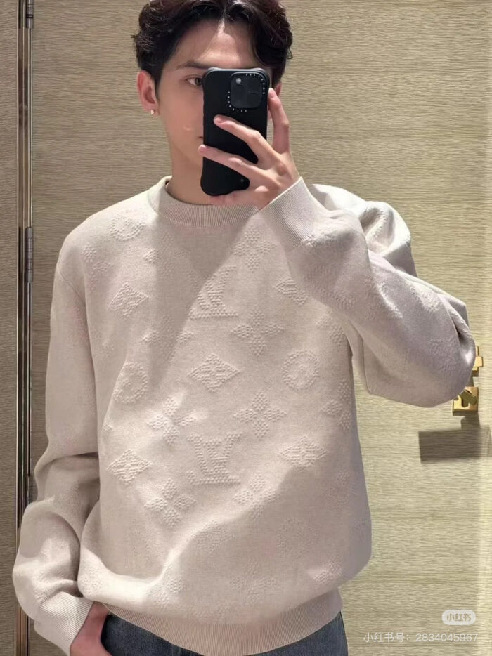 Ragazzo scatta selfie con maglione beige casual e stile moderno in ambiente caldo e accogliente.