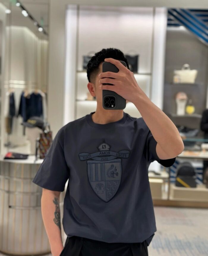 Ragazzo fashion selfie in negozio moderno con t-shirt logo e ambiente minimalista.