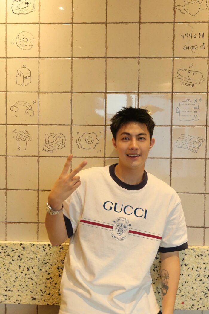 Ragazzo sorridente in un bar moderno con pareti decorate da disegni food artistici.